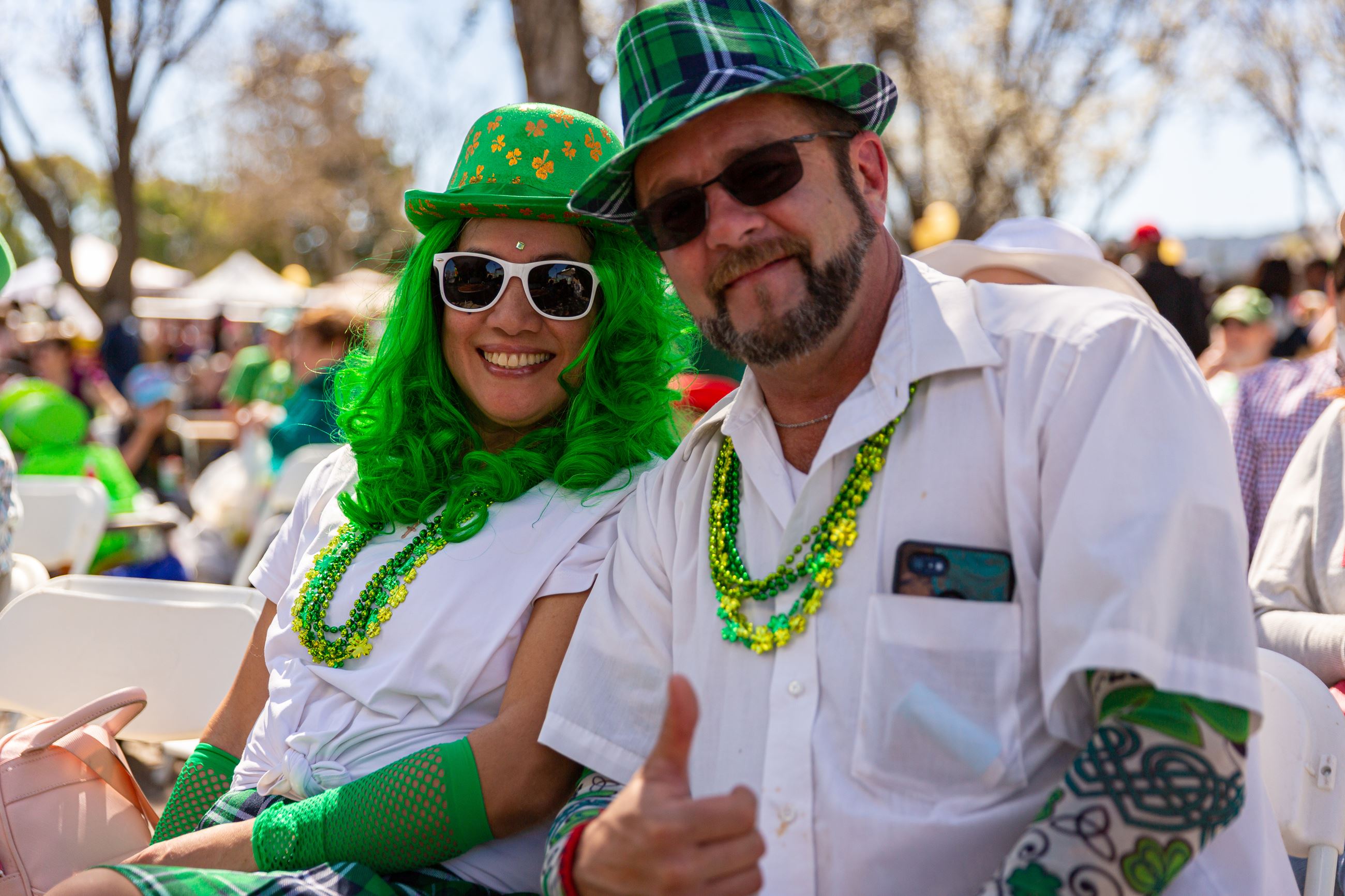 Woman with green hair and man with green sequined hat sitting in plaza at Dublin Civic Center at St.