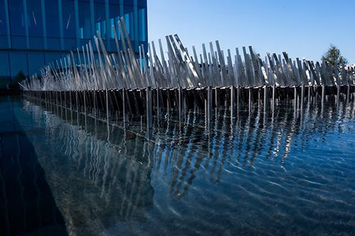 moving metal blades over a pool of water, designed to look like grass blowing in the wind.